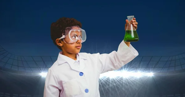 身穿实验室外套的男孩拿着化学瓶面对着有复制空间的体育场的复合图像 体育竞赛和教育概念 — 图库照片