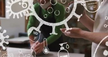 Çömlekçilik atölyesinde yüz maskesi takan insanların üzerinde covid 19 hücre ve simge animasyonu. küresel covid 19 salgını ve işyeri konsepti dijital olarak oluşturulmuş video.