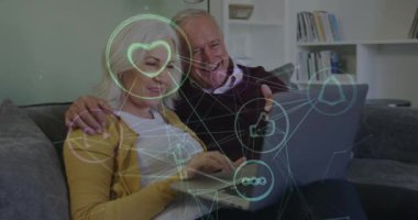 Üst düzey beyaz çiftlerin dizüstü bilgisayar kullanarak medya simgelerinin canlandırılması. küresel iş, finans, bağlantılar ve dijital arayüz konsepti dijital olarak oluşturulmuş video.