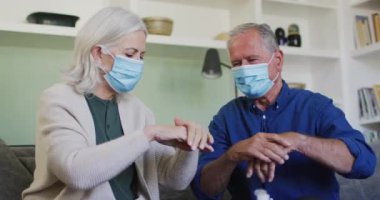 El dezenfekte eden yüz maskeli yaşlı beyaz çift üzerinde virüs hücrelerinin canlandırılması. Coronavirus covid 19 salgını sırasında tıbbi ve sağlık hizmetleri dijital olarak üretilen video konsepti.