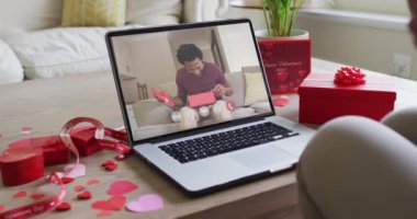 Afro-Amerikalı adamın hediyesini açması ve sevgililer günü videosunu dizüstü bilgisayarına kaydetmesi. Sevgililer Günü kutlaması, romantizm ve iletişim teknolojisi.