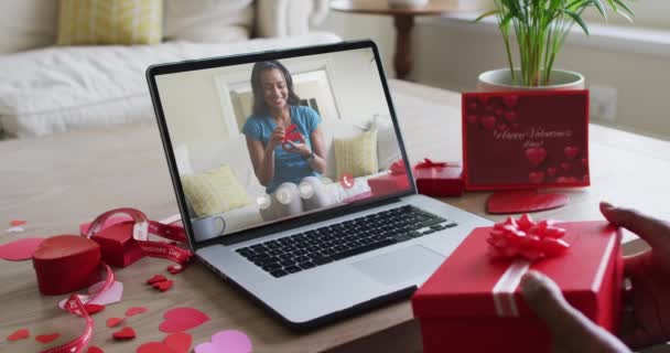 幸せなアフリカ系アメリカ人女性が贈り物を開き ノートパソコンでバレンタインデーのビデオ通話をします バレンタインデーのお祝いロマンス通信技術 — ストック動画