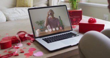 Şaraplı melez bir adam dizüstü bilgisayarında Sevgililer Günü videosu çekiyor. Sevgililer Günü kutlaması, romantizm ve iletişim teknolojisi.