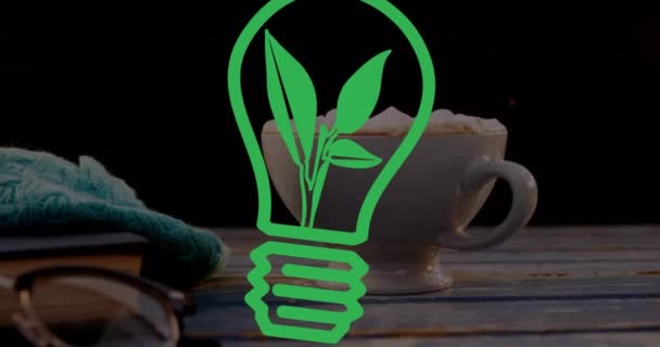 黒を背景にコーヒーカップの上に緑の電球のアニメーション 地球環境 グリーンエネルギー デジタルインターフェースの概念をデジタルで生成し — ストック動画