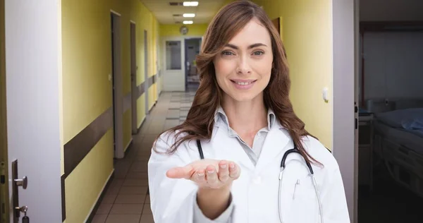 病院の廊下に立っている間にジェスチャー中の大人の白人女性医師の笑顔の肖像画 コピースペース世界癌の日聴診器廊下医療病院のコンセプト — ストック写真