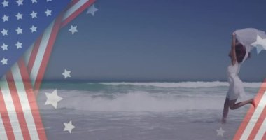 Sahilde elini kaldıran Afro-Amerikan kadının Amerikan bayrağının animasyonu. Vatanseverlik ve kutlama konsepti dijital olarak oluşturulmuş video.