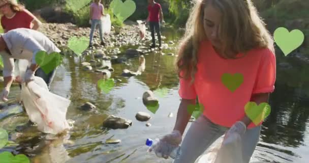 田舎でゴミを拾う多様な幸せなグループの上に緑の心のアニメーション 環境保全ボランティアの月デジタル生成ビデオ — ストック動画