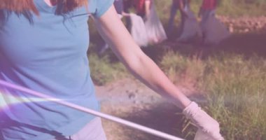 Kırsal kesimdeki gönüllülerle çöpleri toplayan mutlu beyaz kadın üzerine ışık videosu. Çevre koruma gönüllü ayı dijital video.