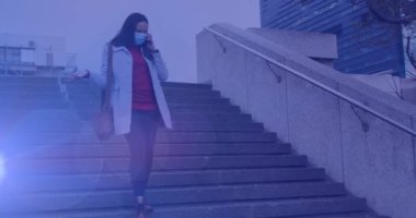 Sokak ortasında akıllı telefon kullanan, maske takan çift ırklı bir kadının mercek patlaması videosu. İşe yürüyerek gidildiği gün, şehirdeki banliyö sakinleri covid 19 salgını sırasında dijital ortamda video çekiyorlar..