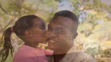 Mutlu Afro-Amerikan askerinin kızını taşıması üzerine ağaçların animasyonu. Vatanseverlik ve kutlama konsepti dijital olarak oluşturulmuş video.