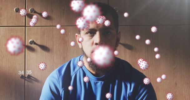 Animacja Komórek Wirusa Unoszących Się Nad Dwurasowym Męskim Futbolistą Szatni — Wideo stockowe