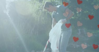 Kırsal kesimde güneşli bir günde çöpleri toplayan beyaz adamın üzerinde hareket eden kalplerin animasyonu. Çevre koruma gönüllüsü ayı dijital olarak oluşturulmuş video.