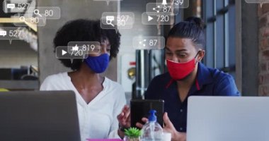 Yüz maskesi takan ve teknolojiyi kullanan melez insanların üzerine düşen ikonların videosu. covid 19 salgın konsepti sırasında dijital olarak üretilen küresel ağlar, iş ve bağlantılar.