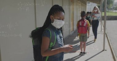 Çeşitli okul çocukları ve yüz maskesi takan öğretmenlerin matematik denklemlerinin animasyonu. okul, eğitim ve öğrenim covid 19 pandemik konsept dijital olarak oluşturulmuş video.