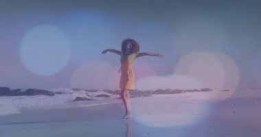 Sahilde dans eden Afrikalı Amerikalı bir kadının üzerindeki ışık noktalarının canlandırması. yürüyüş günü ve dijital olarak oluşturulan video konsepti.