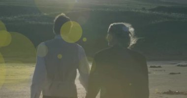 Kafkasyalı bir çiftin el ele tutuşup yürümesi üzerine ışıklı noktaların canlandırılması. yürüyüş günü ve dijital olarak oluşturulan video konsepti.