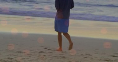 Sahilde yürüyen melez bir kadının üzerindeki ışık lekelerinin canlandırması. yürüyüş günü ve dijital olarak oluşturulan video konsepti.