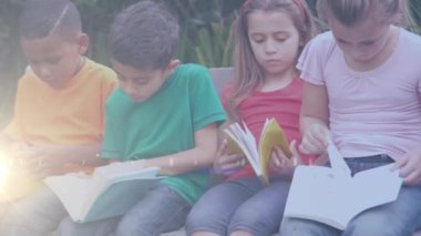 Kitap okuyan çeşitli okul çocukları üzerindeki ışık izlerinin animasyonu. Çocuk kitabı günü ve dijital olarak oluşturulan kutlama konsepti.