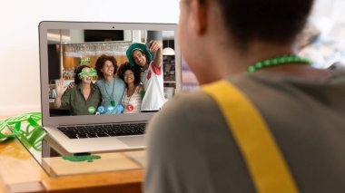 Karışık ırk kadını, evdeki bilgisayardaki çeşitli arkadaş gruplarına Aziz Patrick Günü videosu çekiyor. Karantina süresince evde tecrit edilmiş İrlandalı koruyucu azizlerin gününü kutluyoruz..