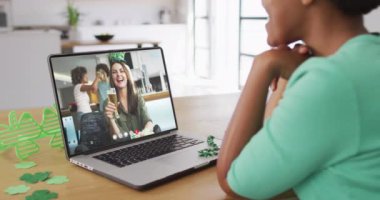 Laptopta görüntülü arama yaparken yonca şekilli bant takan beyaz bir kadın gülümsüyor. İrlanda geleneği ve Aziz Patrick Günü kutlama konsepti dijital olarak oluşturulmuş video.