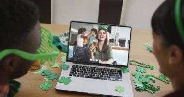 Laptopta görüntülü arama yaparken yonca şekilli bant takan beyaz bir kadın gülümsüyor. İrlanda geleneği ve Aziz Patrick Günü kutlama konsepti dijital olarak oluşturulmuş video.