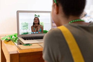 Karışık ırk kadını, St. Patrick 'in günü videosuyla dizüstü bilgisayarda öpüşen kadını arıyor. Karantina süresince evde tecrit edilmiş İrlandalı koruyucu azizlerin gününü kutluyoruz..