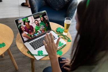 Bira içen beyaz bir kadın barda dizüstü bilgisayardan arkadaşlarına Aziz Patrick günü görüntülü arama yaptırıyor. İrlanda Koruyucu Azizler Günü 'nün kutlaması sırasında.