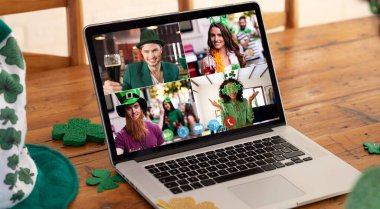 Farklı kostümlü arkadaşlar St. Patrick 'in günü görüntülerini evdeki dizüstü bilgisayarlarda gösteriyorlar. Karantina süresince evde tecrit edilmiş İrlandalı koruyucu azizlerin gününü kutluyoruz..