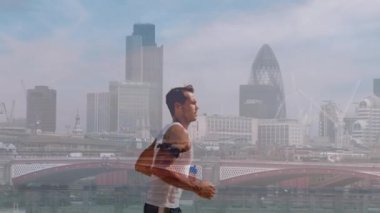 Kafkas erkek koşucunun Londra şehir manzarasında bir şişe suyla koşuşması. Londra maratonu ve spor konsepti dijital olarak üretilen video.