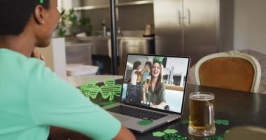 Laptopta görüntülü arama yaparken yonca şekilli bant takan beyaz bir kadın gülümsüyor. İrlanda geleneği ve Aziz Patrick Günü kutlama konsepti dijital olarak oluşturulmuş video.