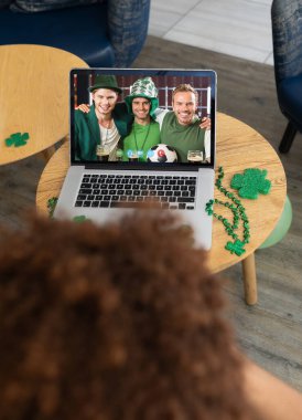 Bardaki karışık yarış adamı dizüstü bilgisayar ekranında gülümseyen erkek arkadaşlarına Aziz Patrick günü videosu çekiyor. İrlanda Koruyucu Azizler Günü 'nün kutlaması sırasında.