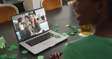 Laptopta görüntülü arama yaparken yonca şekilli bant takan beyaz bir kadın gülümsüyor. İrlanda geleneği ve Aziz Patrick Günü kutlama konsepti dijital olarak oluşturulmuş video.