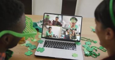 Laptop 'taki görüntülü aramada gülen, biralı, yonca şekilli eşyalar giyen bir grup arkadaş. İrlanda geleneği ve Aziz Patrick Günü kutlama konsepti dijital olarak oluşturulmuş video.