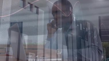 Akıllı telefon ve dizüstü bilgisayar kullanarak Afro-Amerikan adamını hareket ettiren finansal veri ve grafiklerin animasyonu. küresel iş, finans, borsa ve teknoloji konsepti dijital olarak oluşturulmuş video.