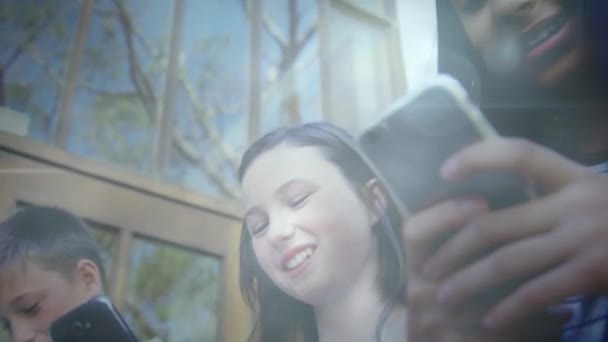 スマートフォンを屋外で使用して幸せな多様なティーンエイジャーの学生のグループ上のボケのアニメーション 社会的つながり技術と学校教育の概念デジタルで生成されたビデオ — ストック動画