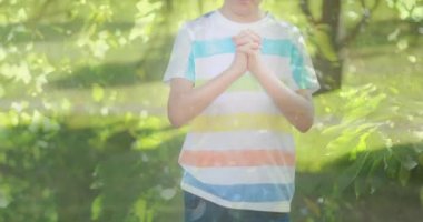 Arka planda yeşil ağaçlar üzerinde dua eden beyaz çocuk animasyonu. din, inanç ve Hıristiyanlık kavramı dijital olarak oluşturulmuş video.