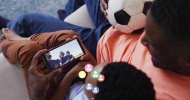Afrika kökenli Amerikalı baba ve oğlunun akıllı telefondan futbol izlemesi üzerine sosyal medya ikonlarının canlandırılması. küresel sosyal medya, dijital arayüz ve dijital olarak oluşturulan öğrenme konsepti.
