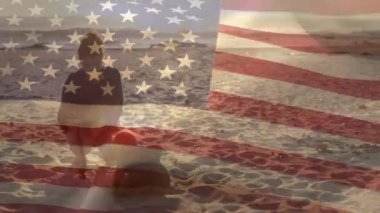 Amerikan bayrağının sahilde bebekle oynayan beyaz bir annenin üzerindeki canlandırması. Vatanseverlik ve kutlama konsepti dijital olarak oluşturulmuş video.