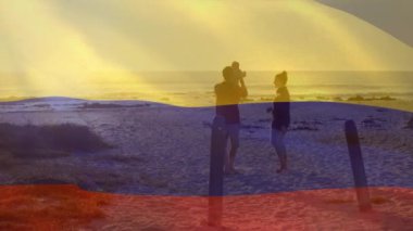 Kolombiya bayrağının plajda çocuklu beyaz ebeveynler üzerinde canlandırılması. Vatanseverlik ve kutlama konsepti dijital olarak oluşturulmuş video.