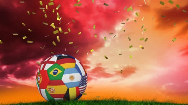 日没時に芝生の上に様々な国旗が横たわっているボールの上に落ちてくるコンフェッティのアニメーション スポーツと競争の概念をデジタルで生成し — ストック動画