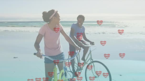 在海滩上骑自行车的快乐的非洲裔美国夫妇的心像动画 时装和生活方式概念数码视频 — 图库视频影像