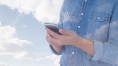 Akıllı telefon kullanan beyaz adamın üzerindeki bulutların animasyonu. Kot günü ve kutlama konsepti dijital olarak oluşturulmuş video.