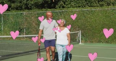 Kıdemli Afro-Amerikan çiftin tenis oynadıktan sonra kucaklaşması üzerine pembe kalplerin animasyonu. communication, love, beraberlik, sağlık ve refah konsepti dijital olarak oluşturulmuş video.