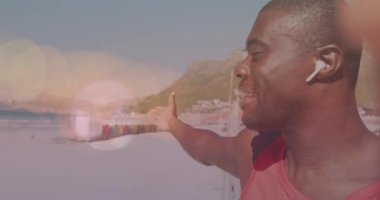 Sahilde gülümseyen Afrikalı Amerikalı bir adamın üzerinde ışık lekeleri. sağlık ve zindelik kavramı dijital olarak oluşturulmuş video.