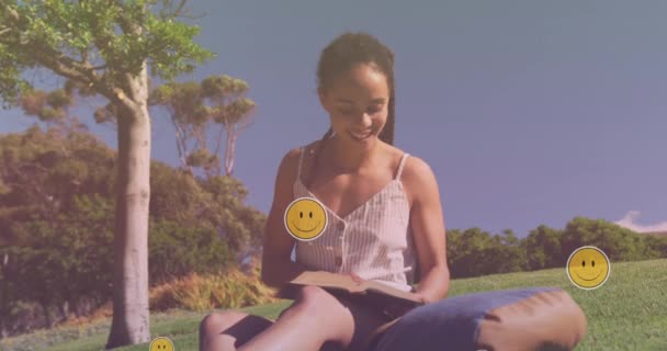 Animazione Icone Emoji Sopra Sorridente Donna Biraciale Che Legge Nel — Video Stock