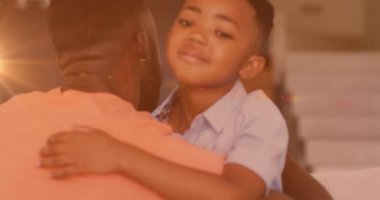 Mutlu Afro-Amerikan baba ve oğlunun evde kucaklaşması üzerine ışık animasyonu. aile, birliktelik, kaliteli zaman konsepti dijital olarak oluşturulmuş video.