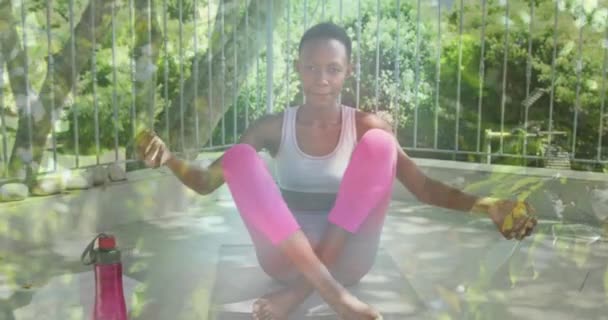 非洲裔美国妇女练习瑜伽和冥想时的叶子动画 世界冥想日和数字制作的视频庆祝概念 — 图库视频影像
