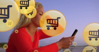 Kumsalda akıllı telefon kullanan beyaz bir kadının orta bölümündeki alışveriş simgelerinin canlandırılması. küresel bağlantılar, çevrimiçi alışveriş, teknoloji ve dijital arayüz konsepti dijital olarak oluşturulmuş video.