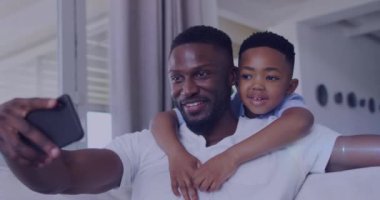 Mutlu Afro-Amerikan baba ve oğlunun selfie çekmesi üzerine ışık animasyonu. aile, birliktelik, teknoloji konseptiyle dijital olarak oluşturulmuş video ile zaman geçirme.