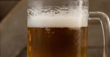 Arka planda bira bardağına yaslanan yonca yaprağının animasyonu. Aziz Patrick Günü kutlamaları ve dijital olarak üretilen İrlanda geleneği..